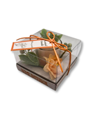 lumanare decorativa in pahar cu decor floral peach, frunze pastel si bobite albe, ambalata in cutie transparenta cu funda portocalie